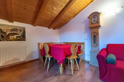 a dining room with a table and a clock at Apartments Agave in Ortisei