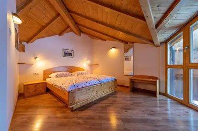 a bedroom with a large bed and a wooden ceiling at Apartments Agave in Ortisei