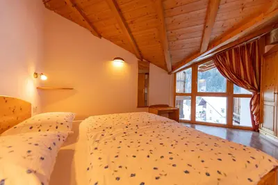 a bedroom with a bed and a large window at Apartments Agave in Ortisei