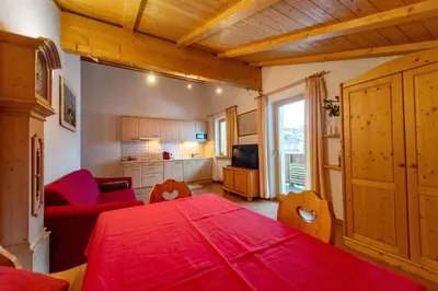 a living room with a red table and a kitchen at Apartments Agave in Ortisei