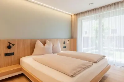 a bedroom with a bed with a large window at VANEA - Alp Relax Guesthouse in Chienes