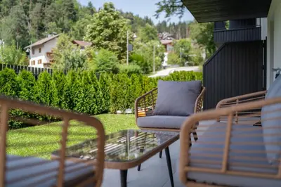 a patio with a couch and chairs on a porch at VANEA - Alp Relax Guesthouse in Chienes