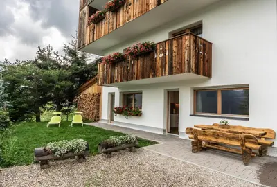 a house with a wooden balcony and two benches at Cresta in San Cassiano