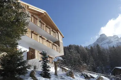 a building in the snow with mountains in the background at Cresta in San Cassiano
