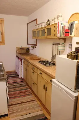 a kitchen with wooden cabinets and a white refrigerator at Ronchet Baita Vanoi Trentino in Ronco