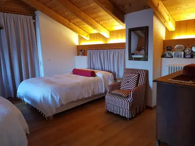 a bedroom with a bed and a chair in it at Ronchet Baita Vanoi Trentino in Ronco
