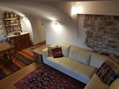 a living room with a white couch and a stone wall at Ronchet Baita Vanoi Trentino in Ronco