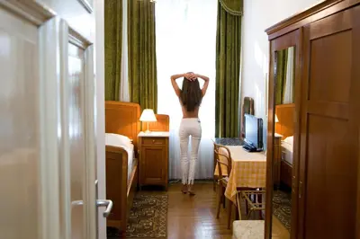 a woman standing in a hotel room looking out the window at Hotel Villa Westend in Merano
