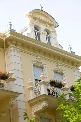 a building with two windows and a balcony with flowers at Hotel Villa Westend in Merano