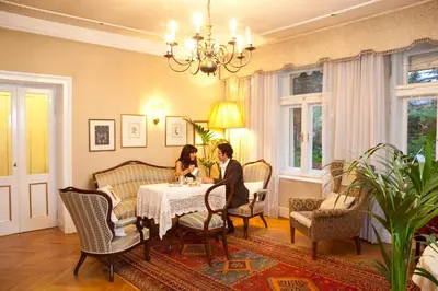 a man and woman sitting at a table in a living room at Hotel Villa Westend in Merano