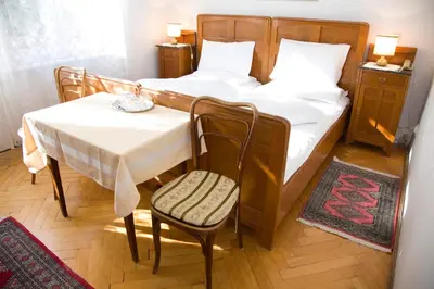 a bedroom with a bed and a table and chair at Hotel Villa Westend in Merano