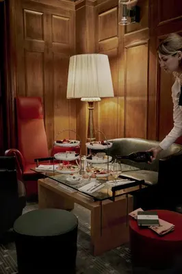 a woman standing in a room with a table with glasses at Parkhotel Laurin in Bolzano