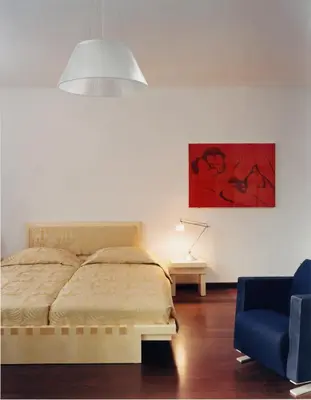 a bedroom with a bed and a blue chair at Hotel Greif, a Member of Design Hotels in Bolzano