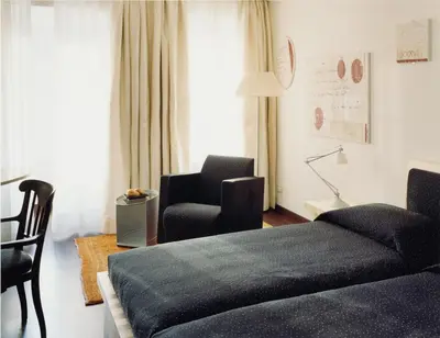 a living room with a bed and a chair at Hotel Greif, a Member of Design Hotels in Bolzano