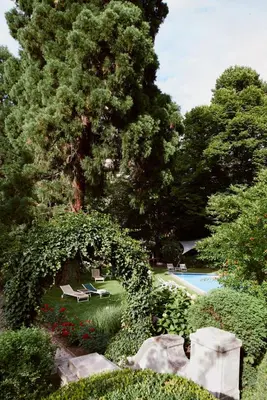 a garden with a tree and a swimming pool at Hotel Greif, a Member of Design Hotels in Bolzano