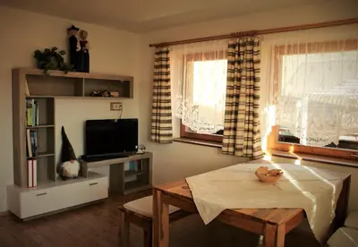 a living room with a table and a tv at Lü de Terza in San Vigilio Di Marebbe