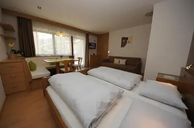 a bedroom with two beds and a living room at Ciasa Wallis in Badia