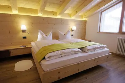 a bedroom with a large bed with a wooden wall at Ciasa Wallis in Badia