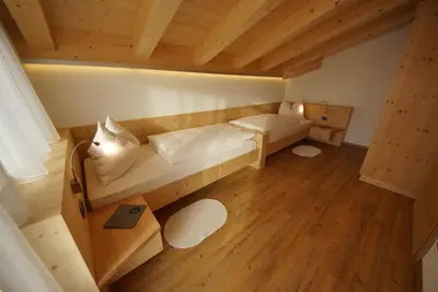 a room with two beds and a wooden floor at Ciasa Wallis in Badia