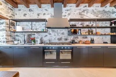 a kitchen with stainless steel appliances and a stone wall at Villa Molin Del Faure in Alleghe