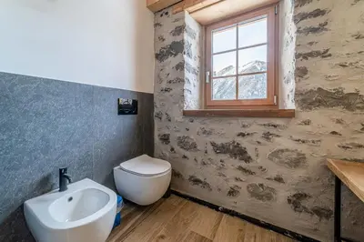 a bathroom with a sink and a toilet and a window at Villa Molin Del Faure in Alleghe