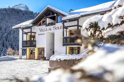 a building with snow on the ground in front of it at Residence Villa al Sole in Selva di Val Gardena