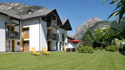 two chairs on a lawn in front of a building at Residence Villa al Sole in Selva di Val Gardena