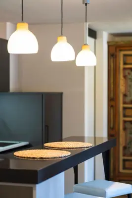 a kitchen with two stools and three pendant lights at Ciasa Buro - Ron in Moena