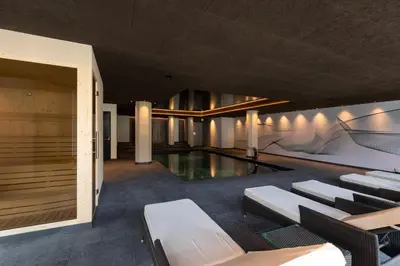 a building with a pool and chairs and a swimming pool at Am Brunnen Apartments in Naz-Sciaves