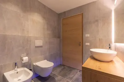 a bathroom with a white sink and a toilet at Am Brunnen Apartments in Naz-Sciaves