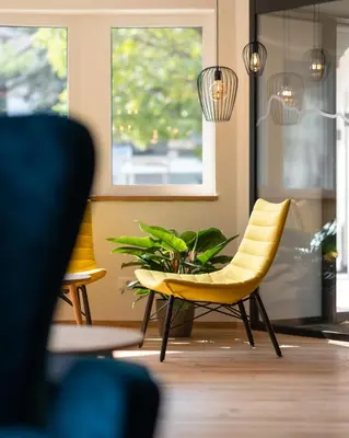 a yellow chair and a plant in a room at Am Brunnen Apartments in Naz-Sciaves