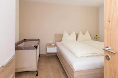 a bedroom with a large white bed with white pillows at Wiedmairhof in Villa Ottone