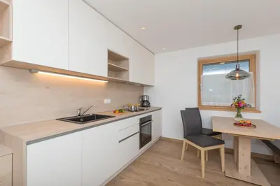 a kitchen with white cabinets and a table and a chair at Wiedmairhof in Villa Ottone