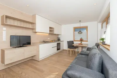a living room with a gray couch and a kitchen at Wiedmairhof in Villa Ottone