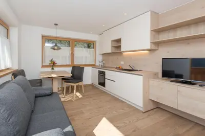 a kitchen and living room with a couch and a tv at Wiedmairhof in Villa Ottone