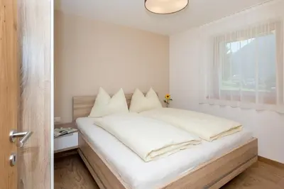 a bedroom with a bed with white sheets and a window at Wiedmairhof in Villa Ottone