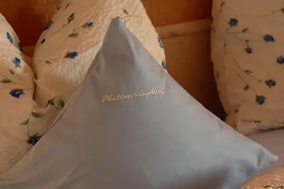 a white bag sitting on a bed with pillows at Plattenriegelhof in Appiano sulla Strada del Vino