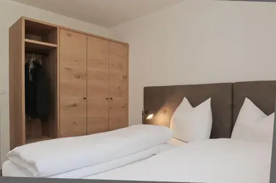 a bedroom with two beds and a closet at Plattenriegelhof in Appiano sulla Strada del Vino