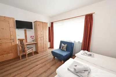 a hotel room with a bed and a chair and a tv at Gasthof Jägerheim in Bressanone