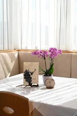 a table with a vase with purple flowers on it at Gasthof Jägerheim in Bressanone