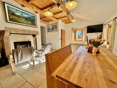 a living room with a wooden table and a fireplace at Chalet Paradisi in Castello Tesino