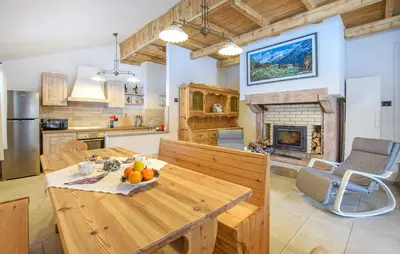 a kitchen and living room with a table and a fireplace at Chalet Paradisi in Castello Tesino