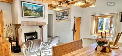 a living room with a table and a fireplace at Chalet Paradisi in Castello Tesino