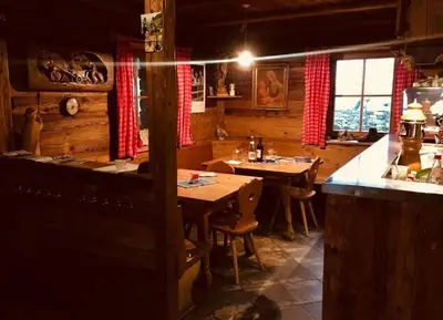 a restaurant with wooden tables and chairs in a room at Almgasthaus Flecknerhütte in San Leonardo in Passiria