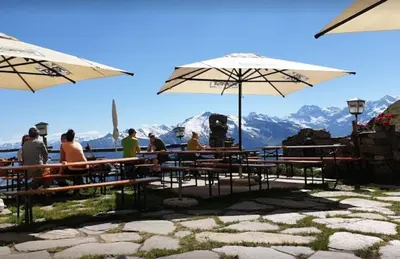 a group of people sitting at a table with umbrellas at Almgasthaus Flecknerhütte in San Leonardo in Passiria