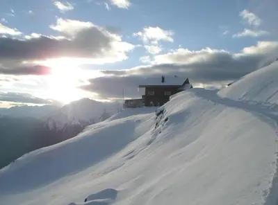 a building on top of a snow covered mountain at Almgasthaus Flecknerhütte in San Leonardo in Passiria