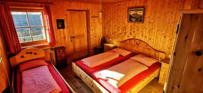 a bedroom with two beds in a wooden room at Almgasthaus Flecknerhütte in San Leonardo in Passiria