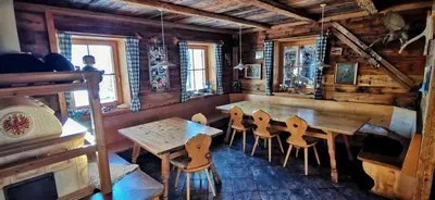 a dining room with a wooden table and chairs at Almgasthaus Flecknerhütte in San Leonardo in Passiria