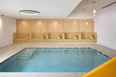 a swimming pool in a room with a couch at Movi Family Apart-Hotel ****s in Corvara in Badia
