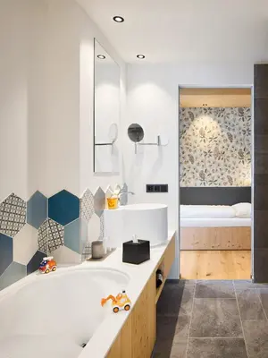 a bathroom with a tub and a bedroom with a bed at Movi Family Apart-Hotel ****s in Corvara in Badia